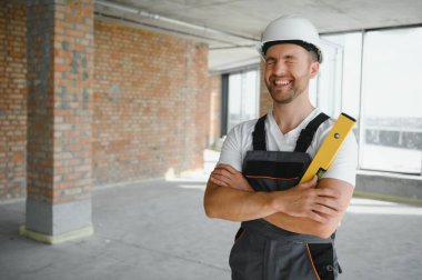 Portrait of handsome male builder in overalls and hard hat.