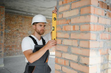Portrait of handsome male builder in overalls and hard hat.