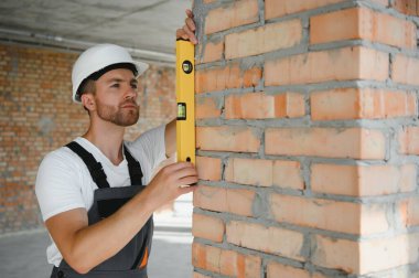 Man builder working in construction site. Male repairer in overall and helmet