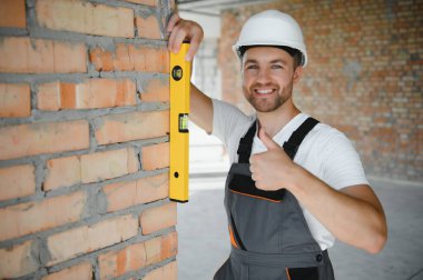 Man builder working in construction site. Male repairer in overall and helmet