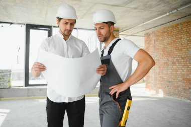 Male Architect Giving Instructions To His Foreman At Construction Site
