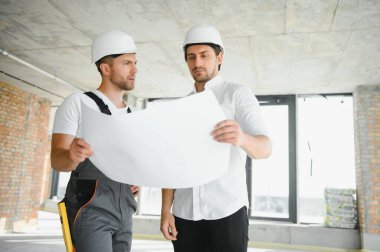 Male Architect Giving Instructions To His Foreman At Construction Site