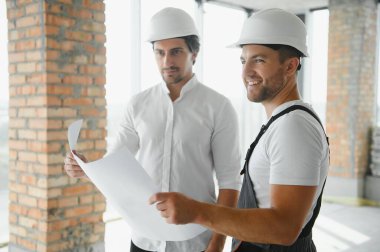 Male Architect Giving Instructions To His Foreman At Construction Site