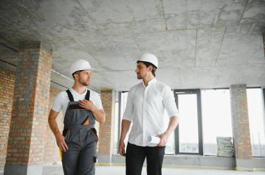 Male Architect Giving Instructions To His Foreman At Construction Site