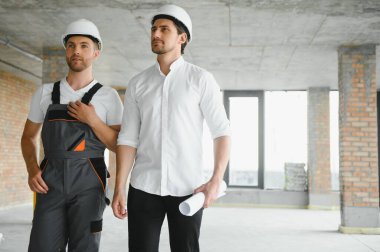 Engineer and worker checking project at building site background, construction site at sunset in evening time.