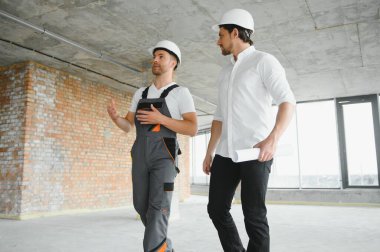 Male Architect Giving Instructions To His Foreman At Construction Site