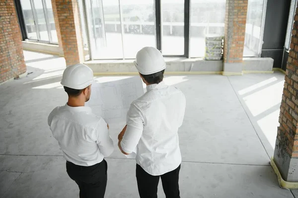 Two Specialists Inspect Commercial, Industrial Building Construction Site. Real Estate Project with Civil Engineer.