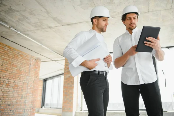Two young man architect on a building construction site.