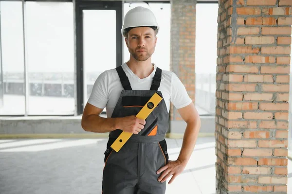 Man builder working in construction site. Male repairer in overall and helmet