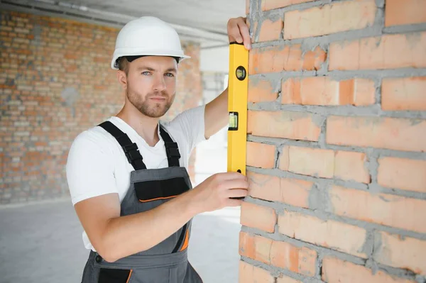 Portrait of handsome male builder in overalls and hard hat.