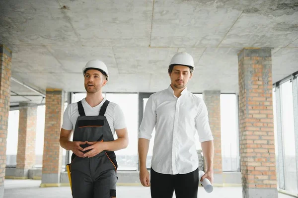 Male Architect Giving Instructions To His Foreman At Construction Site