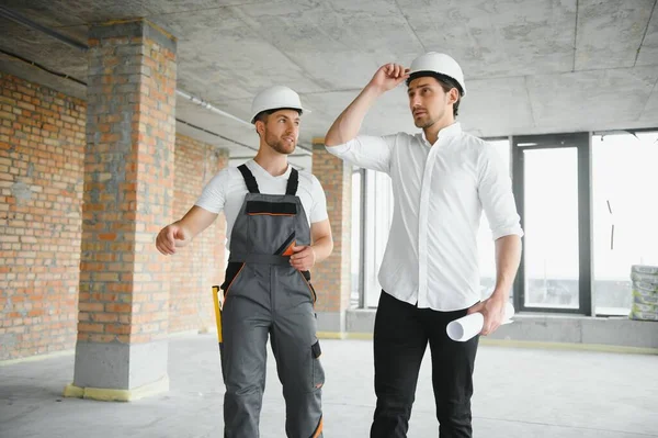 Male Architect Giving Instructions To His Foreman At Construction Site