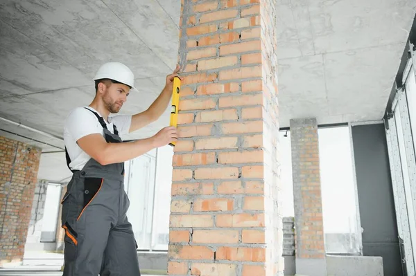 Man builder working in construction site. Male repairer in overall and helmet