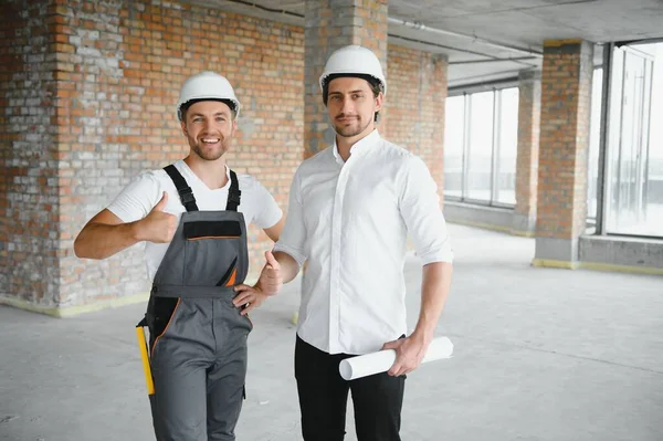 Male Architect Giving Instructions To His Foreman At Construction Site