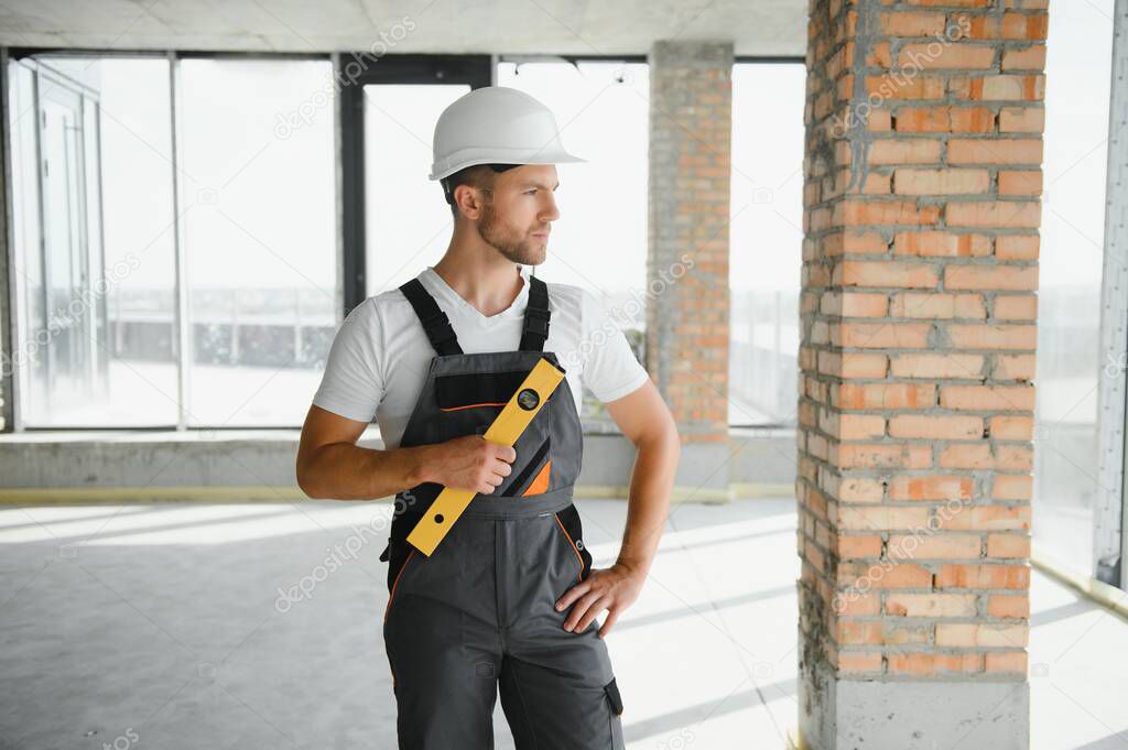 Portrait of handsome male builder in overalls and hard hat.
