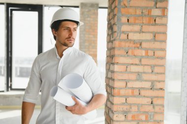 Business architect man wearing hardhat standing of a building project.