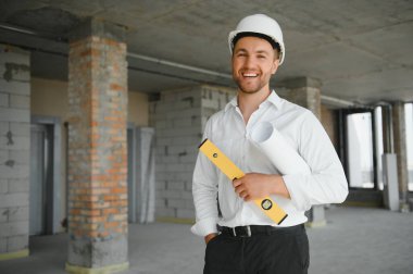 Portrait of man architect at building site. Confident construction manager wearing hardhat. Successful mature civil engineer at construction site with copy space