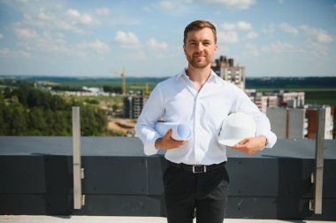 Business architect man wearing hardhat standing of a building project.