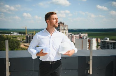 Business architect man wearing hardhat standing of a building project.