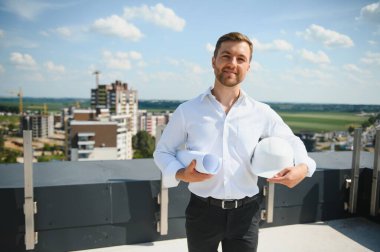 Business architect man wearing hardhat standing of a building project.