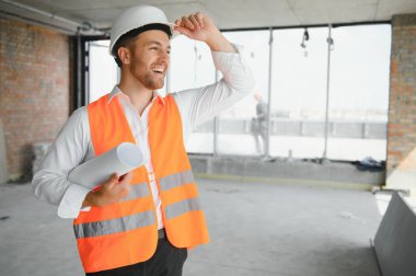 Portrait of man architect at building site. Confident construction manager wearing hardhat. Successful mature civil engineer at construction site with copy space