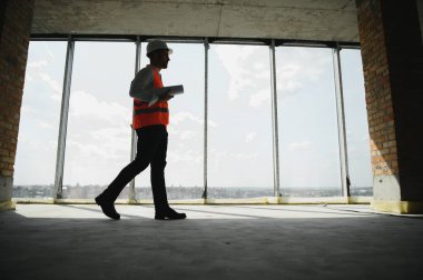 İnşaat alanında çalışan mühendislerin elinde planlar var. Mühendislik ve mimarlık konsepti..