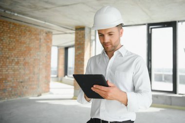 Business architect man wearing hardhat standing of a building project.
