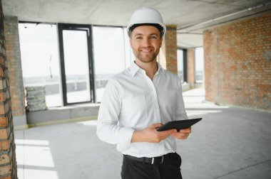 Business architect man wearing hardhat standing of a building project.