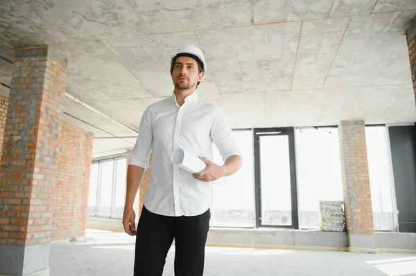 Portrait of man architect at building site. Confident construction manager wearing hardhat. Successful mature civil engineer at construction site with copy space