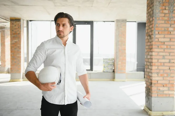 Portrait of man architect at building site. Confident construction manager wearing hardhat. Successful mature civil engineer at construction site with copy space