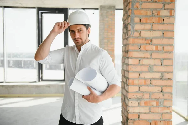 Portrait of man architect at building site. Confident construction manager wearing hardhat. Successful mature civil engineer at construction site with copy space