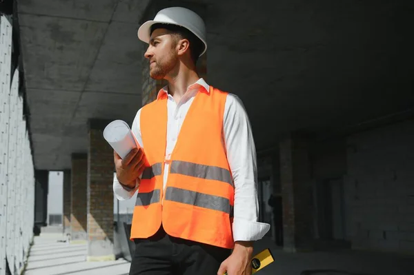 Portrait of man architect at building site. Confident construction manager wearing hardhat. Successful mature civil engineer at construction site with copy space