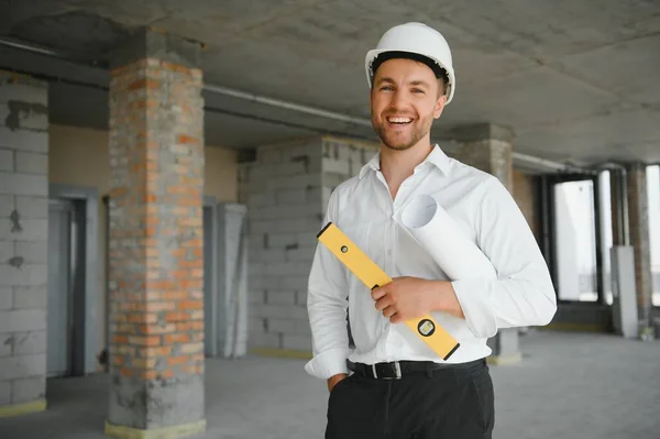 Portrait of man architect at building site. Confident construction manager wearing hardhat. Successful mature civil engineer at construction site with copy space