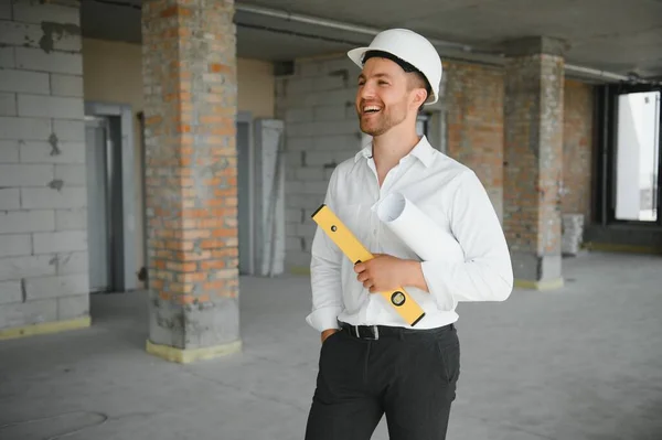 Portrait of man architect at building site. Confident construction manager wearing hardhat. Successful mature civil engineer at construction site with copy space