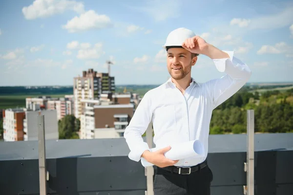 Portrait of man architect at building site. Confident construction manager wearing hardhat. Successful mature civil engineer at construction site with copy space