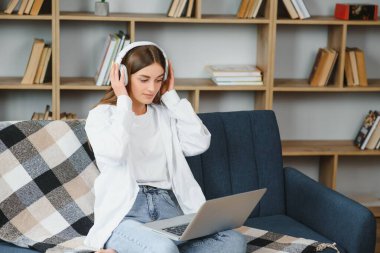 young woman at home on sofa wearing headphones