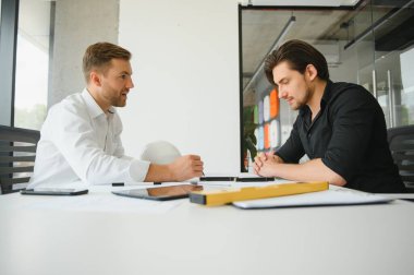 Two colleagues discussing data working on architectural project at construction site at desk in office.