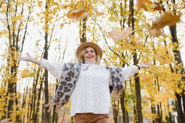 Doğada sonbahar yaprakları tutan tatlı, gülen kadın.