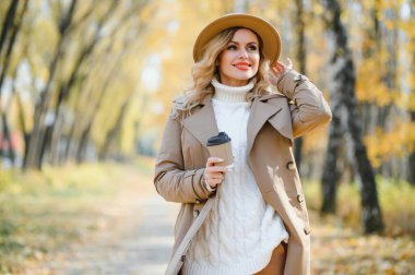 Happy smiling young woman in park on autumn day