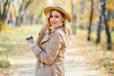 Happy smiling young woman in park on autumn day