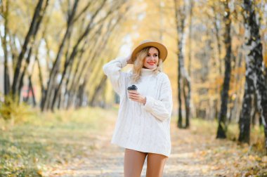 Kahve fincanı sonbahar parkta olan genç ve güzel kadın.