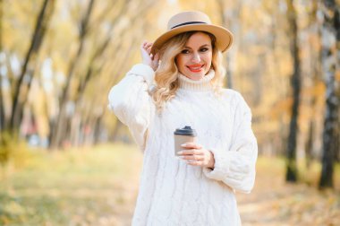 Happy smiling young woman in park on autumn day