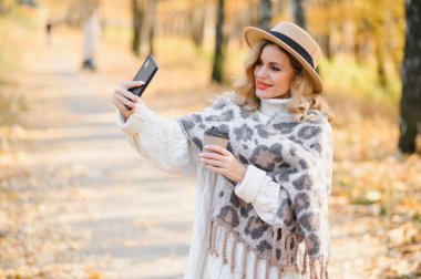 Kahve fincanı sonbahar parkta olan genç ve güzel kadın.