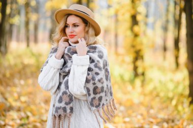 Happy smiling young woman in park on autumn day