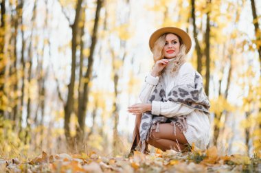 Happy smiling young woman in park on autumn day