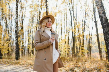 Kahve fincanı sonbahar parkta olan genç ve güzel kadın.