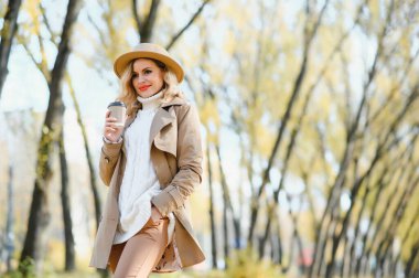 Kahve fincanı sonbahar parkta olan genç ve güzel kadın.