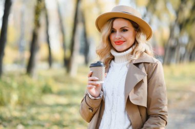 Happy smiling young woman in park on autumn day