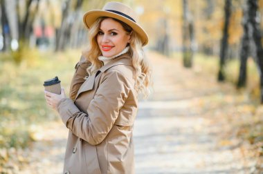 Kahve fincanı sonbahar parkta olan genç ve güzel kadın.