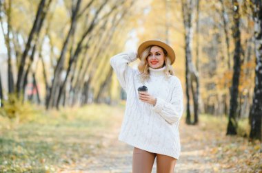 Happy smiling young woman in park on autumn day